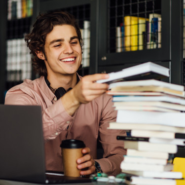Man looking at books whilst holding a coffee